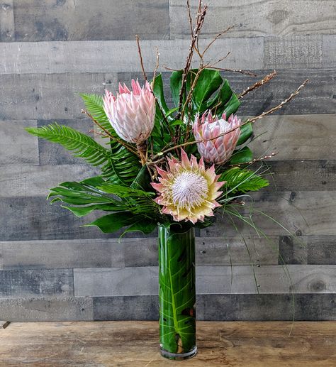 Bar arrangement with pink king protea with monstera leaves. #Harringtonflowers #barflowers #bedfordvillageinn #protea #tropicalflowers #kingprotea Protea Arrangements Vase, King Protea Flower Arrangements, King Protea Arrangement, Protea Arrangements Modern, Protea Flower Arrangements, Protea Arrangements, Protea Centerpiece, Modern Centrepiece, Bar Arrangement