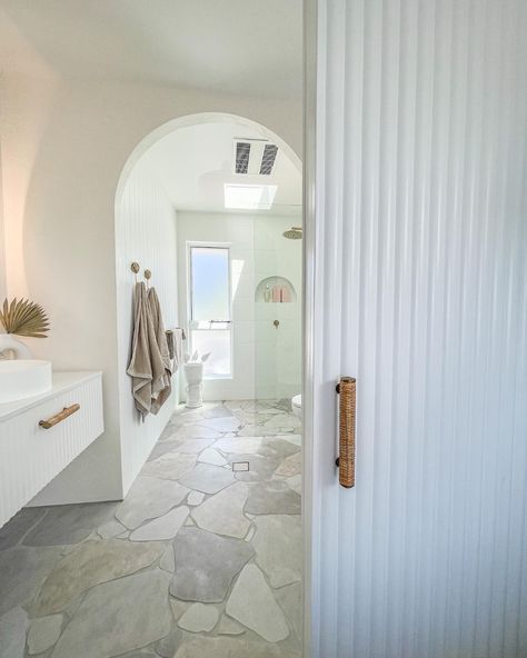 This bathroom was in urgent need of the coastal ensuite makeover and that's what it got. In this renovated bathroom, we see a gorgeous white scalloped door with wicker handles blocking the coastal bathroom. With other features like the stone pave flooring, scalloped vanity, white walls and arch highlighted, you can really enjoy this day spa style bathroom! To see this renovated bathroom in one of our real Australian home tours, click on the pin or go to StyleCurator.com.au. Ensuite Makeover, Stone Floor Bathroom, Stone Tile Bathroom, Coastal Bathroom Design, Spa Style Bathroom, Crazy Paving, Coastal Bathrooms, Bathroom Design Inspiration, Unique Bathroom