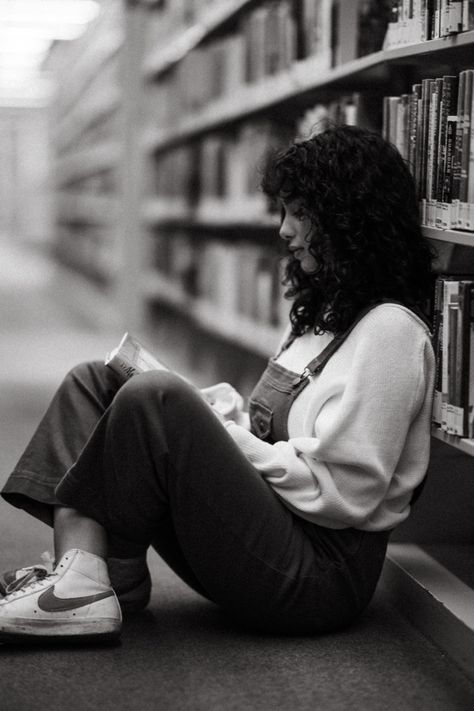 A black and white photograph of a woman sitting on the ground of a library reading a book. Cute Library Pictures, Photography Poses In Library, Photo Shoot In Library, Photography In Library, Photoshoot Moodboard Inspiration, Photoshoot In A Library, Vintage Library Photoshoot, Photoshoot Library Photo Ideas, Photoshoot In Bookstore