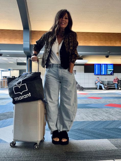 Woman posing at the airport dressed in barrel leg jeans, white shirt, black vest, and black sandals. Puddle Jeans Street Style, Barrel Denim Outfit, Baloon Jeans Styling Women, Barrel Jeans Outfit Spring, Diy Barrel Jeans, Free People Barrel Jeans, Barrel Jeans Outfit Street Style, Barrel Jean Outfit Ideas, Ballon Jeans Outfits