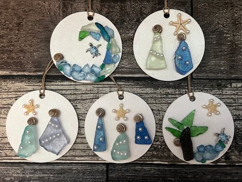 Round wood circles are painted white and a sparkle top coat is added before adding a holiday/coastal scene using sea glass, crushed glass, shells, flat back petals, starfish, small jewelry findings or pebbles. A piece of hemp twine is added for hanging. Each ornament is truly unique. Order any 2 for 27.99 and save!  If you have a request please message me. Choose the number on the ornaments in the photos to receive the specific ornament pictured. if you are ordering 2 for 27.99 please message me the numbers at checkout. These will make a great addition to your coastal tree, or a  special gift for a beach lover. Sea Glass Ornaments Christmas, Beach Glass Ornaments, Sea Glass Ornaments Diy, Sea Glass Christmas Ornaments, Sea Glass Ornaments, Shell Christmas Ornaments, Glass Ornaments Diy, Coastal Tree, Handblown Glass Ornaments