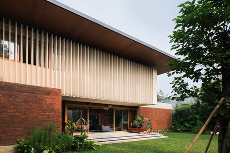 Located in the heart of South Jakarta, this house was designed as a response to the tropical climate. The building consists of 3 main masses, the front is the semi-public area which includes a garage, service area, powder room, and working room. The front part is a brick rectangular box with a compressed wooden ceiling, creating a transitional entrance to the main area. Every room is designed with a big opening to have good air circulation and natural light. Mid Century Modern Exterior, Big Balcony, Studio 17, Floating Stairs, Wooden Ceilings, Big Windows, Patio Designs, Modern Tropical, Tropical Houses