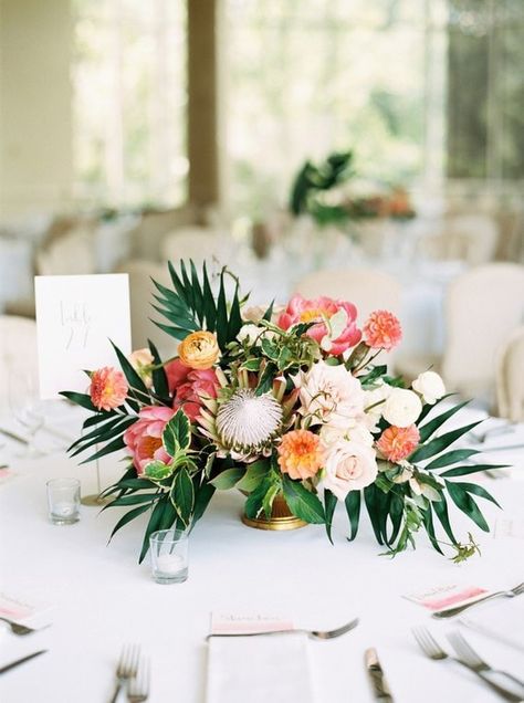 Tropical wedding centrepiece with palm leaves, protea and peony in coral, orange, pink and yellow | Hannah Mayson Photo via 100 Layer Cake Tropical Wedding Centerpieces, Tropical Centerpieces, Tropical Wedding Theme, Tropical Wedding Flowers, Flowers And Greenery, Wedding Floral Centerpieces, Coral Wedding, Beach Wedding Favors, Flower Centerpieces Wedding