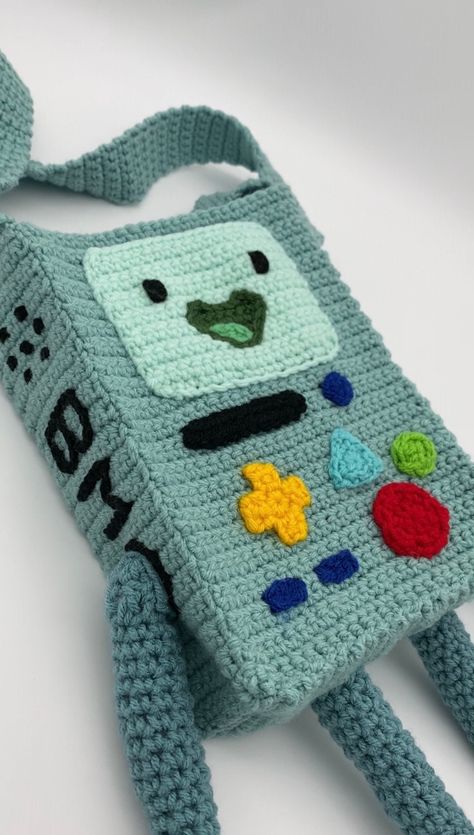 *I have not yet made the bag. It will take me up to three weeks to complete it* Here is the completed version of the BMO bag!! I make the straps 34 in (86cm) long. If you want a different length. Put it in the message seller box when purchasing bag or if you're seeing this after you bought it, message me separately! Average strap lengths Short Handle : 12-20in (30-51cm)  Shoulder : 30in (76cm) Long Shoulder : 40in (102cm)  Crossbody : 50in (127cm) Keep in mind the length of BMO : about 9in (23cm Crossbody Bag Crochet Pattern, Cool Crochet Bags, How To Knit A Bag, School Bag Crochet, Funny Crochet Bag, Bmo Crochet Pattern Free, Crochet Messenger Bag Free Pattern, Bmo Cosplay, Crochet Bean Bag