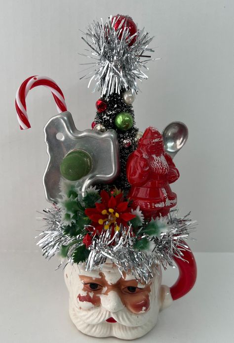 Vintage Santa Mug Assemblage/Vintage Plastic Santa/Christmas Decoration This vintage Santa mug with his sweet face showing his age has been created with a fun assemblage with a vintage Santa cookie cutter, vintage teaspoon,  and a hard plastic Santa. The bottle brush tree has new and vintage glass ornaments and beads. Lots of fun silver tinsel and vintage plastic greenery with a flocked poinsettia completes Santa's look! It would look adorable sitting on a kitchen cabinet for Christmas! Caution: Vintage Christmas Assemblages, Decorating With Santas, Diy Vintage Christmas Decor, Christmas Assemblage, Christmas Kisses, Christmas Planter, Vintage Glass Ornaments, Santa Cups, Primitive Christmas Decorating