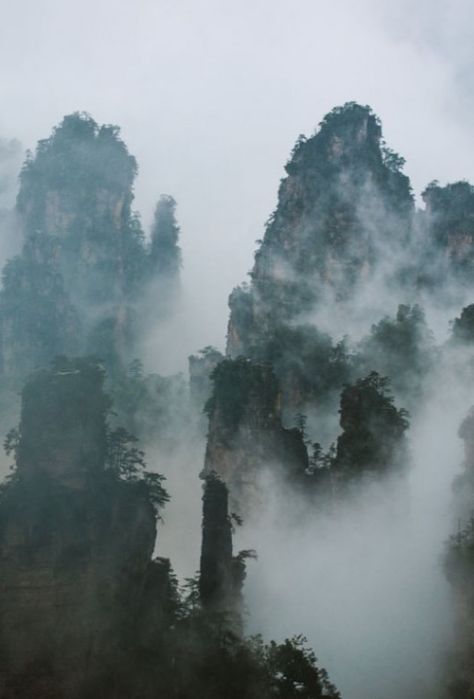 WULINGYUAN, China: is noted for more than 3,000 quartzite sandstone pillars & peaks, many over 660 ft in height, along with ravines, gorges, streams, pools, & waterfalls. It features 40 caves, many with large calcite deposits, & two natural bridges, Xianrenqiao (Bridge of the Immortals) & Tianqiashengkong (Bridge Across the Sky). Wulingyuan forms part of the Wuling Mountain Range, which formed by 700 million years ago. Mountains In China, Mountain Kingdom Aesthetic, China Mountains, Ancient China Aesthetic, Mountain Kingdom, Mountain China, Chinese Bridge, Chinese Deserts, Chinese Mountains