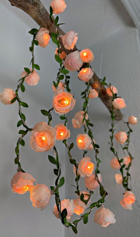 This magical fairy lights with 40 small roses and leaf garland creates a fairytale atmosphere. It fits in every room, but can also be used on the balcony or spread their romantic light on the terrace. It is powered by electricity and can be used flexibly thanks to its 4 meter cable. There is one on each of the 40 LED lights small plastic bush rose attached and the illuminated length is wrapped with an artificial leaf garland. You can choose between these three flower colors: Delicate cream Playf Flower Wall Lights, Aesthetic Fairy Lights, Pink Fairy Lights, Fairy Room, Small Roses, Rose Fairy, Romantic Room, Flower Colors, Light Chain