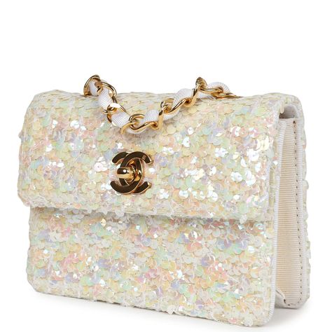 This Vintage micro half flap bag quilted iridescent ivory sequin and ribbed satin with gold hardware, features tonal stitching, cc turnlock closure, interwoven gold tone chain link and white canvas fabric crossbody/shoulder strap.The interior is lined in ribbed ivory satin fabric.Collection: 1-series (1989-1991)Origin: FranceCondition: Vintage; Excellent to Mint - This bag retains its shape and structure. The exterior shows some minor signs of wear with a few loose threads and sequins. The hardware has light scratching. The interior fabric is slightly discolored on interior base but all around clean and date stamp sticker still intact.Accompanied by: Chanel dustbagMeasurements: 5.5" width x 4" height x 1" depth; 21" strap drop Sparkly Designer Bags, White Chanel Bag, Fendi Purse, Vintage Chanel Bag, Dream Bags, Vintage Chanel Handbags, Sequin Bag, Chanel Purse, Luxury Purses