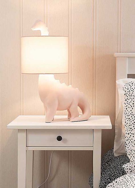 Brighten up your little ones space with this dinosaur shaped table lamp. The ceramic base comes in a pink or green finish with a matching braided flex and fabric drum shade. Give your child's bedroom a pop of colour in a subtle and fun way. The in-line rocker switch provides convenient control, making it easy to illuminate your space. Help your child overcome the fear of darkness and create a comfortable sleep environment with this playful lamp. Brand: ValueLights Ceramic Dimensions approx. 26 x Girly Dinosaur Room, Pink Dinosaur Nursery, Girls Dinosaur Bedroom, Girl Dinosaur Room, Dinosaur Bedroom Ideas, Dinosaur Themed Bedroom, Dino Lamp, Dinosaur Baby Room, Fear Of Darkness