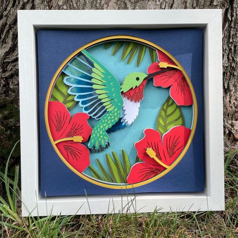 "I will be unable to ship until after Jan 1, 2024. Gorgeous 3D picture of a hummingbird feeding at a flower. This 13-layer design is made using glitter, foil, shimmer, and matte card stock. The picture measures 8.25\" x 8.25\". The black shadowbox frame measures 9.875\"x9.875\"x1.75\".  Design by Christina Ritch. The picture(s) you receive might vary slightly from the picture shown due to the nature of the picture being handmade. All the pictures are hand-assembled, one at a time, making creation of identical items difficult. If you live in the Leavenworth/Lansing/Tonganoxie, KS local area, message me to make pickup arrangements and I can credit some of the item price." Layered Cricut Projects, Hummingbird Svg, 3d Paper Projects, Crafts Cricut, Product Sale, Shadow Box Svg, 3d Shadow Box, 3d Paper Crafts, Cricut Creations