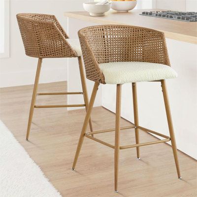 This coastal-inspired counter stool set adds a breezy, textured look to your kitchen or dining area. Each stool features a full back with a natural rattan backrest and armrests that are both breathable and stylish. Supported by sleek metal legs with a wood-inspired finish, these stools boast a modern aesthetic that complements your space. The gently curved chair back and foam-padded seat are upholstered in beige boucle fabric, providing a cozy spot for you and your guests. Complete with a footrest and metal glides for floor protection, these counter stools are not only fashionable but functional, too. | Bay Isle Home™ Arm Counter Stool Upholstered / Wicker / Rattan in Beige | 27" H | Wayfair Woven Bar Stools Overstock, Counter Stools Kitchen Island Uk, French Country Bar Stools Target, Kitchen Counter Top Seating, Bar Stools Kitchen Island Wicker, Bar Stools Kitchen Island Target, Rattan Dining Room Furniture, Ratton Kitchen Table, Island Chairs Uk