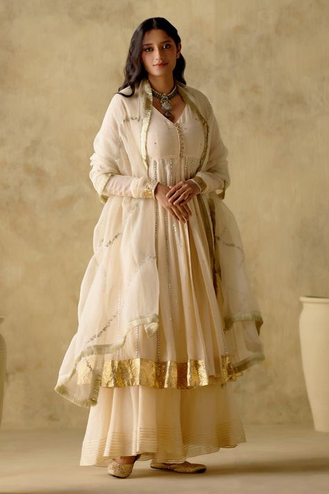 Ivory anarkali with zari, patra work and finished with gota lace embroidery. Paired with sharara and embroidered dupatta. Components: 3 Pattern: Embroidered Type Of Work: Floral Neckline: V neck Sleeve Type: Full Fabric: Anarkali and Sharara: chanderi silk lined with mul cotton, Dupatta: Organza Color: Ivory Other Details:  Gathered detailing Button detailing Attached lining Fringe detailing on dupatta Occasion: Wedding - Aza Fashions Gown Indian Wedding, Suit Anarkali, Floral Anarkali, Silk Anarkali, Cotton Anarkali, Anarkali Gown, Cocktail Reception, Sharara Set, Wedding Lehenga