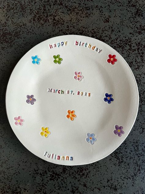 A personalized Happy Birthday ceramic hand built plate, a perfect gift for girls and boys.  Your special text with lots of flowers, stars, little cars, daisy...etc. If you could not choose, because you have your own idea, I will paint for you. The dessert plate is made from a white ceramic clay, I wrote a text with colorful under-glaze and painted in the centre a little figure. I used letterpress technique and carve a pattern to the clay before painting. The last shiny layer is a transparent, cl Daisy Pottery Painting Ideas, 1st Birthday Plate Diy, Happy Birthday Pottery Plate, First Birthday Plate Ideas, Birthday Plate Ideas Girl, Special Day Plate, Homemade Birthday Plate, Ceramic Pottery Plate, Pottery Painting Birthday Plate