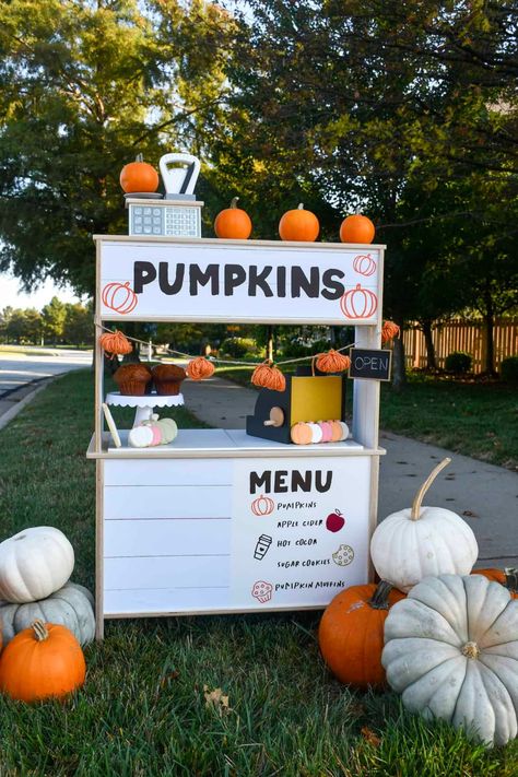 Decorated pumpkin stand made from the Ikea play kitchen. Has toys on it and pumpkins around it. Fall Lemonade Stand, Ikea Duktig Hack, Ikea Duktig Kitchen, Pumpkin Menu, Duktig Kitchen, Fall Bake Sale, Apple Cider Cookies, Stall Decorations, Diy Lemonade Stand