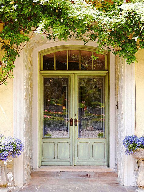 The prettiest details offer unmatched elegance against the washed-out paint finish of this mostly glass front door. Splendid in size, the double door relies on an excess of glass in both the doors and the five-paned transom overhead. While many standard doors are set flush onto the facade of a home, this one instead has a deep recess, boosting its romantic appeal. Bright Front Doors, French Front Doors, Front Door Makeover, Beautiful Front Doors, European Doors, Farmhouse Front Door, Double Front Doors, Front Door Entrance, Farmhouse Front