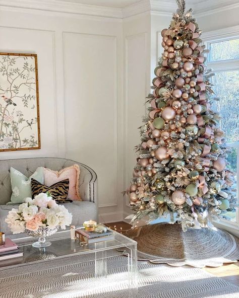 A tufted gray living room sofa is accentuated by a colorful arrangement of accent pillows. Pink, green, and gold decorations adorn a tree that displays Christmas tree skirt ideas. The jute tree skirt surrounds the tree base overlapping a patterned gray rug...   Image: littlelattihouse Jute Tree, Pink Christmas Tree Decorations, Hallmark Christmas Tree, Full Christmas Tree, Flocked Trees, Minimalist Apartment, Flocked Christmas Trees, Candy Christmas, Pink Christmas Tree