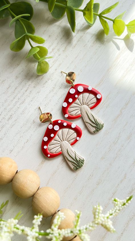 These handmade polymer clay mushroom dangle earrings are perfect for adding a touch of whimsy to any outfit. Each pair is crafted with care to ensure a unique and one-of-a-kind piece of jewelry. The earrings feature cute mushroom designs in red with white spots, dangling from delicate 18K gold plated brass circle. The lightweight design makes them comfortable to wear all day long, and the lead and cadmium free and nickel posts make them safe for most sensitive ears. Wandering Calico Clay earring Cottagecore Earrings Clay, Mushroom Earrings Polymer Clay, Mushroom Clay Earrings, Polymer Clay Mushroom Earrings, Clay Mushroom Earrings, Earrings Mushroom, Mushroom Designs, Polymer Clay Mushroom, Ladybug Jewelry