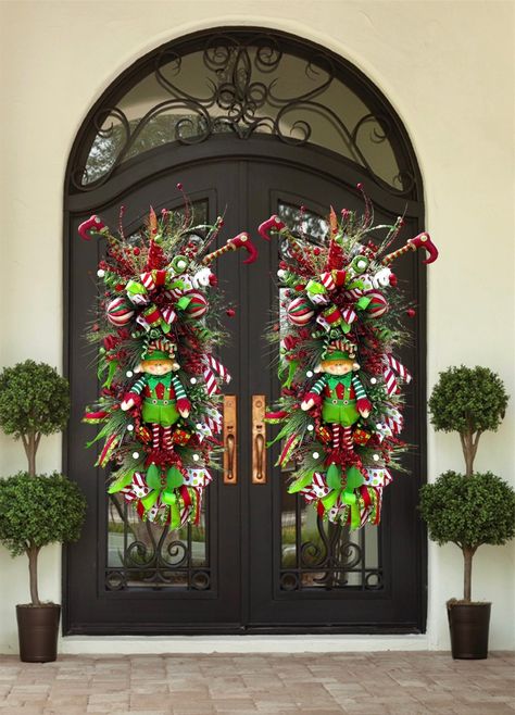 xtra Large Christmas Elf Wreath for Double Doors | Nice Elf Christmas Theme Swag For Front Door | Red, White, Gold Christmas Decor Merry Christmas, Happy Holidays, and a Happy New Years everyone! Introducing a brand new elf swag. This wreath has a large red sparkly bow, made with both red ribbon and white/ green ribbon with a white and black satin pattern in the center. This ribbon is about 4 inches thick. On the top of this swag are various sparkly picks in gold, red and light green to match the elf suit. In the center there are different colored ornaments all red, green, and white. A beautiful stuffed elf man in the center with two reflective gift box ornaments on the side. To match the top, on the bottom is the same red  bow and a different all satin ribbon with the same white, green an Garland Christmas Decor Door, Peacock Christmas Wreath, Double Door Wreath Ideas Christmas, Elf Christmas Theme, Double Door Christmas Decor, White Gold Christmas Decor, Red White Gold Christmas, Christmas Swags Ideas, White Gold Christmas