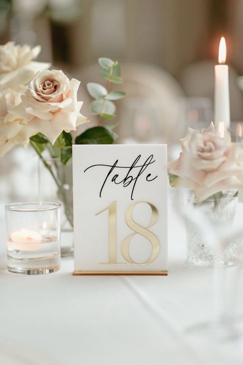 "Elevate Your Table Setting: Add a touch of elegance and sophistication to your wedding tables with our White Acrylic Table Numbers with Gold Mirror Stands. These exquisite signs are designed to enhance your wedding decor, perfectly balancing functionality and style. Chic White Acrylic Numbers: Each table number is beautifully crafted from high-quality white acrylic, ensuring visibility and elegance. The crisp, clean white design offers a modern yet timeless look, ideal for any wedding theme. Luxurious Gold Mirror Stands: Complementing the white acrylic numbers, the gold mirror stands provide a stable and stylish base, adding a touch of glamour and ensuring each number stands out on your tables. Versatile and Timeless Design: Our table numbers are designed to complement any wedding decor, Champagne Table Numbers, Table Designs Wedding, Beige And Gold Wedding Theme, Dog Table Numbers Wedding, Simple Elegant Wedding Decor, Gold And White Wedding Decorations, White And Gold Table Decor, White And Gold Wedding Table, Elegant Wedding Signage