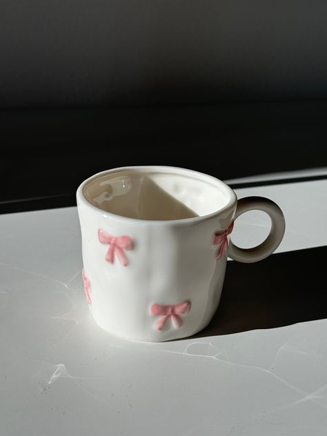 Say hello to the "Marie" Coquette Mug. Each ceramic mug is meticulously handcrafted and hand-painted, making every piece unique. For best care, we recommend hand washing to preserve the beauty and longevity of your Marie Coquette Mug. Elevate your morning routine or afternoon tea with this purr-fectly charming addition to your home. Diameter: 8cm  Height: 7cm Its a tiny mug but not super tiny! Cute Tea Gifts, Dior Mug, Self Care Coquette, Aesthetic Coffee Mugs, Coquette Mugs, Coquette Ceramics, Bow Mug, Mug Shapes Pottery, Gift Ideas Coquette