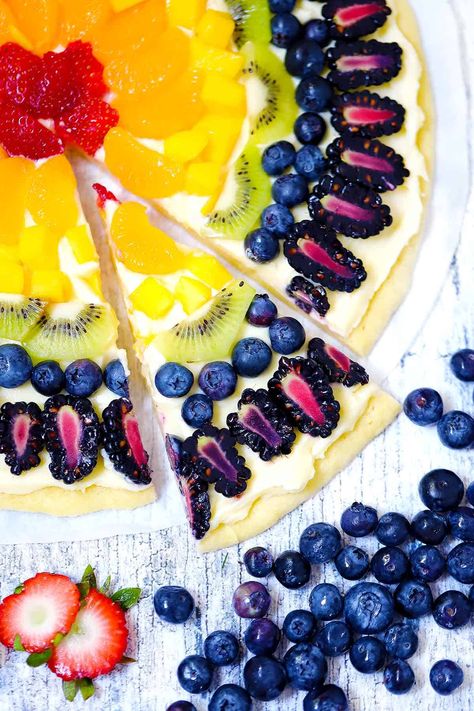 Rainbow Fruit Pizza is a great recipe to celebrate Pride with natural rainbow colors in healthy fruit! A sugar cookie crust is topped with cream cheese frosting and topped with fruit in all the colors of the rainbow for this easy and delicious make ahead dessert recipe that is great for parties, potlucks, or pride celebrations. Fruit Rainbow Cake, Pride Baking, Pride Recipes, Pride Desserts, Rainbow Fruit Pizza, Rainbow Pie, Rainbow Cake Recipe, Fruit Cheesecake, Party Sides