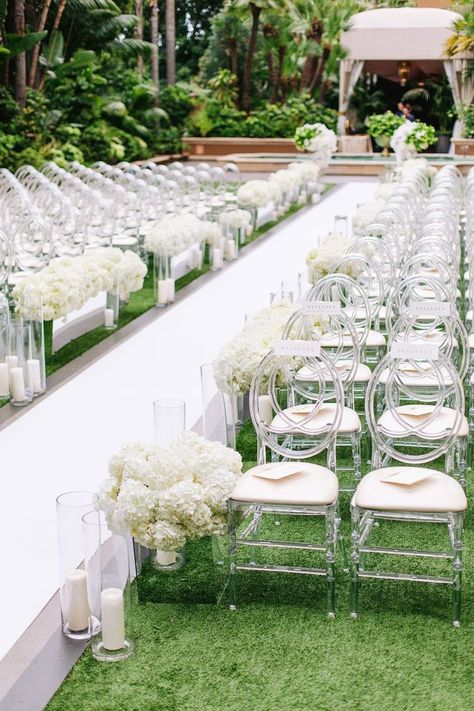 Dec 21, 2020 - Guests found their seats on oval-back acrylic chairs on both sides of a crisp white aisle lined with candles and arrangements of ivory hydrangeas in mirrored b… Sleek And Modern Wedding, Outside Wedding Ceremonies, Wedding Ceremony Chairs, White Wedding Ceremony, Ceremony Florals, White Weddings Reception, White Wedding Decorations, Wedding Isles, Hydrangea Wedding