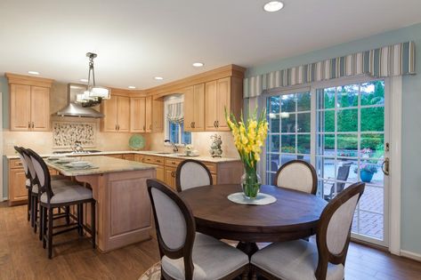 There's nothing more cozy and inviting than an eat-in kitchen with breakfast nook. Here, dark woods are used in the nook as opposed to the light woods in the kitchen, creating a sense of a separate space -- but one that's still connected due to the matching chairs at the kitchen island. Striped windows in both spaces also create a unity. Eat In Kitchen Round Table, Round Table In Kitchen, Kitchen With Sliding Glass Door, Kitchen Sliding Glass Door, Kitchen With Table, Kitchen Round Table, Circular Kitchen Table, Dark Wood Dining Table, Kitchen Table Lighting