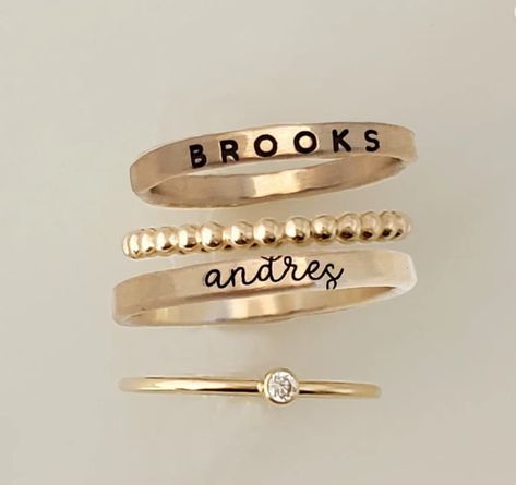 This exquisite personalized ring set is a beautiful way to show your loved one just how special they are. Crafted from high-quality .999 fine silver, 14k yellow gold filled, or 14k rose gold filled, each ring is adorned with a sparkling cubic zirconia stone and can be personalized with a special message. Whether you're celebrating a milestone, expressing your love, or just wanting to make a unique statement, this ring set is the perfect way to do it. With its timeless beauty and thoughtful customization, it's sure to be a cherished piece for years to come. This listing includes 4 rings: - two name rings in your choice of font (see photos and drop down menu for choices) - a thin cz ring - a beaded spacer ring These rings are handmade in our Indiana studio. We use yellow gold solder on our r Names Jewelry, Personalized Stackable Rings, Children Names, Seashell Projects, Mom Ring, Name Ring, Mother Rings, Name Rings, Mom Jewelry