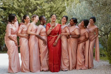 Bridal party with bride in a red lehenga and pink bridesmaids dresses Red Saree Bride With Bridesmaid, Indian Bridesmaids Saree Outfits, Sari Bridesmaid Dress, Indian Bridesmaid Gifts, Pink Bridesmaid Saree, Telugu Bridesmaids Outfits, Bridesmaid In Saree, Tamil Wedding Bridesmaid, Tamil Bridesmaid