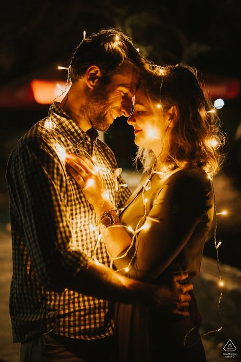 A Topoľčany, Slovakia couple drapes themselves in strands of lights while embracing for their engagement photoshoot with wedding photographer Martin Almasi Photoshoot With Christmas Lights, Night Photography Couple, Photoshoot Ideas Lights, Christmas Lights Photoshoot Couple, Couples Christmas Lights Pictures, Couples Photoshoot Night, Night Couple Photography, Christmas Lights Photoshoot, Couple Photography Winter