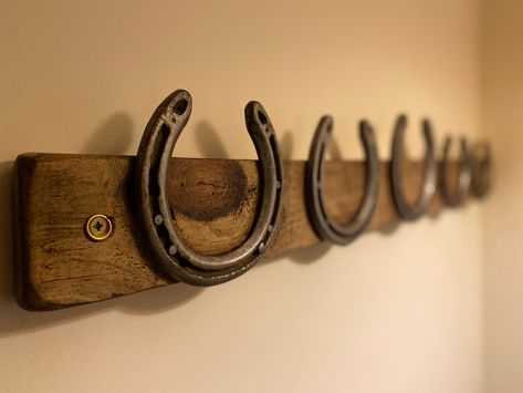 Beautiful wooden coat rack handmade from reclaimed pine with hooks made from horseshoes for a country cottage look. These coat racks would be a great addition to any home.  Coat racks can be made to your spec using 3 - 7 horseshoes.  All racks are hand made to order in our workshop based in Teasdale and come pre drilled for easy installation. Wood is finished in a high quality medium oak wax for a smooth finish whilst accenting the natural grain of the wood. This can be offered in other wood finishes please message  with your requirements. Horse Shoe Shelf, Horse Shoe Coat Hooks, Country Coat Rack, Welded Coat Rack, Horseshoe Home Decor, Horse Shoe Hook, Diy Horseshoe Decor, Diy Horse Shoe Decor, Horse Shoe Hat Rack