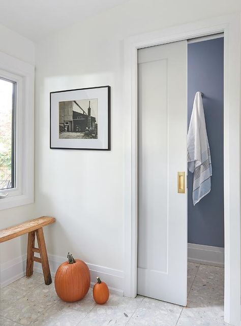 Water closet with a pocket door enters into a space with blue painted walls and towel hooks. Modern Pocket Doors Bathroom Wood, Bathroom Pocket Door Ideas, White Floating Desk, Modern Pocket Doors, Pocket Doors Bathroom, Wood And Metal Desk, White Upper Cabinets, Pocket Door Frame, Blue Painted Walls