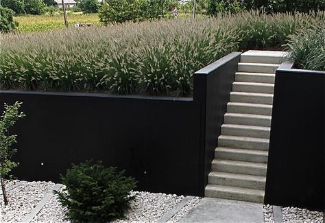 painted retaining wall Charcoal Garden Wall, Black Concrete Retaining Wall, Contemporary Retaining Wall Ideas, Painting Retaining Walls, Black Retaining Wall Garden, Painted Concrete Retaining Wall, Painted Retaining Wall Ideas, Retaining Wall Cover Up Ideas, Black Cinder Block Wall