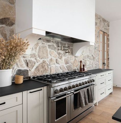 Black Countertop Stone Backsplash, Stone Behind Range, Stone Kitchen Range Hood Ideas, White Kitchen Cabinets Black Countertops Stone Backsplash, Black Countertops Stone Backsplash, Stove Alcove Kitchen Stone, Stone Backsplash Black Countertop, Stone Range Hood Kitchen, Stone Accent Walls Kitchen