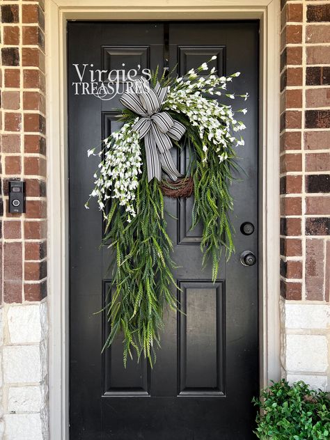 Blossom your surroundings with beautiful blooms. This wreath features foam leaves and paper blooms sporting a solid white color with saw grass stems cascading around the grapevine wreath. Add this lovely wreath to create a unique, one-of-a-kind statement!    Details: Dimensions (Varies Upon Shaping): 35"x22" Plant Type: Flower Bush Material: Foam, Paper & Plastic Color: White & Green Care & Safety: Indoor Use Only Quantity: 1 It is recommended that you keep your wreath under a well covered patio Elegant Door Wreaths, Wreath With Storm Door, Front Door Decor Plants, Contemporary Wreaths For Front Door, Asymmetrical Porch Decor, Wreath For Black Front Door, Double Wreath Ideas, Unique Door Wreaths, Bridal Shower Wreaths For Front Door