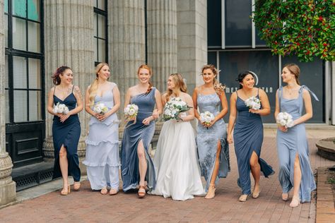 Bridesmaids wearing Dusty blue and navy dresses with different textures and patterns walking with bride in white dress. All are carrying bouquets of peonies. Blue Toned Bridesmaid Dresses, Navy And Dusty Blue Bridesmaid Dresses, Blue Steele Bridesmaid Dresses, Multiple Shades Of Blue Bridesmaid Dresses, Mismatch Navy Bridesmaid Dresses, Small Mismatched Bridal Party, Blue Shades Bridesmaids, Rusty Blue Bridesmaid Dresses, Multiple Blue Bridesmaid Dresses