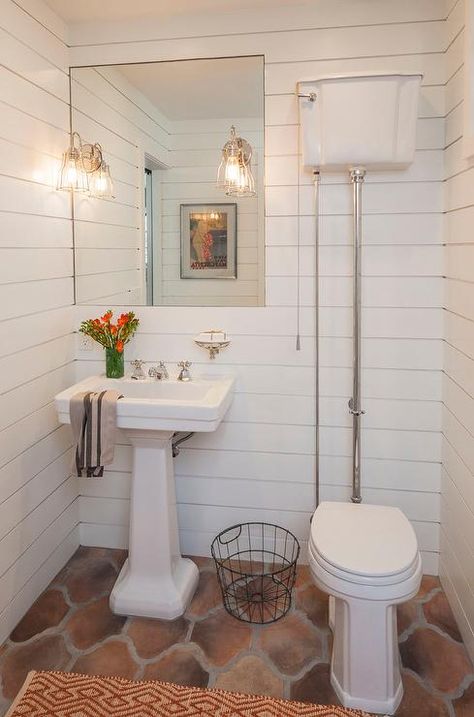 Vintage powder room features  shiplap clad walls lined with an inset mirror illuminated by cage sconces over a pedestal sink  next to an exposed… Terracotta Bathroom Floor, Aesthetic Toilet, Home Depot Bathroom Tile, Beautiful Powder Rooms, Vintage Powder Room, French Country Bathrooms, Exposed Plumbing, Powder Room Design Ideas, Small Powder Room Ideas