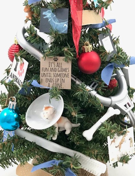 This beautifully decorated tree is perfect for the veterinarian's office!  it is fully decorated with colorful ornaments, a stethoscope, tools, files, heart, syringe, test tube, bones, bandaids, and humorous quotes.  It features a doggie with a cone which will surely bring some smiles.  Show your vet some appreciation this Holiday Season with this wonderful conversation piece!  Perfect size for reception area or desktop. Please note each of our trees and wreaths is individually and uniquely hand Christmas Decor Ideas Doctors Office, Vet Clinic Christmas Decorations, Vet Christmas Decorations, Vet Clinic Christmas Decor, Dog Theme Christmas Tree, Vet Office Decor, Veterinary Nursing, Veterinarian Office, Kennel Ideas