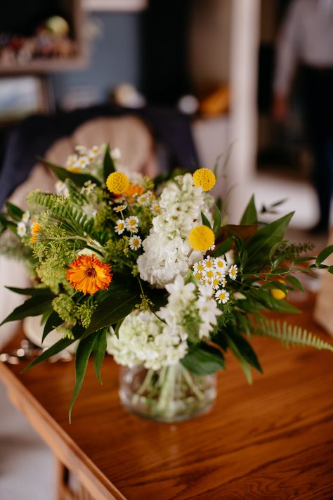 A bridal bouquet in white and green with pops of orange and yellow. This bouquet includes ferns, stock, feverfew, craspedia, calendula, gold grevelia, queen annes lace, phlox. A july wedding in wyoming with flowers by sheridan, WY wedding florist whirly girl flowers. Green Bride Bouquet, Green And White Bridal Bouquet, Fern Centerpiece, Green And White Wedding Flowers, Intimate Family Wedding, Wyoming Elopement, Copper Wedding Arch, White And Green Bouquet, Fern Bouquet