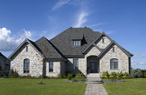 A sturdy-looking luxury stone house in light and dark tones of gray. Houses With Stone Exterior, Grey Stone House Exterior, Grey Stone House, Stone Front House, Stone House Exterior, Brick Roof, Home Gym Design Garage, Stone Exterior Houses, Exterior Houses