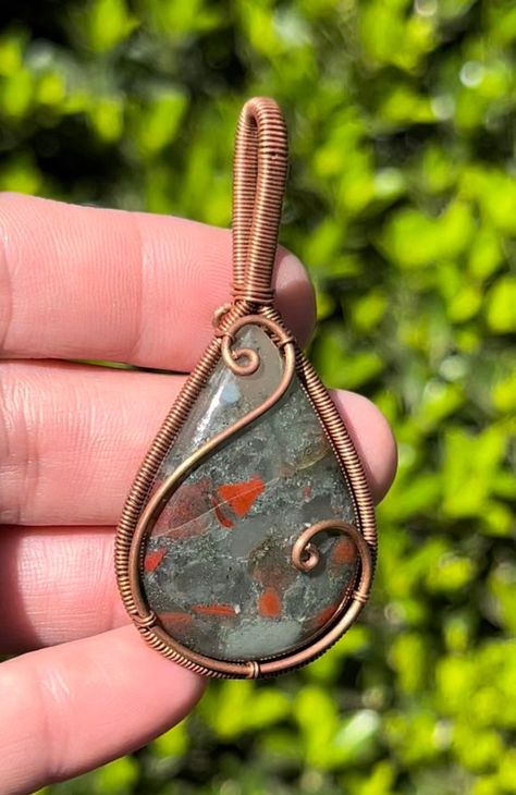 Bloodstone Copper Wire Wrapped Pendant Necklace ~ Handmade Wire Wrapped Crystals ~ Jewelry ~ Genuine stone crystal. Listing is for exact item pictured. Choose either pendant alone or included matching chain. Size Approx: 6x3cm Gemstone Type: Semi-Precious Gemstone Gift wrap optional! *Free shipping over $35 in the US* In the ancient world, Bloodstone (Heliotrope) was considered to be the most beautiful of the Jaspers, a deep, earthy green gem emboldened with spots of bright red. Called the Sun S Wire Wrapped Cabachon Pendants, How To Wire Wrap Gemstones, Rock Wire Wrapping Tutorial, Copper Wrapped Crystals, Small Wire Wrapped Pendant, Mens Wire Wrapped Jewelry, Diy Wire Jewelry Tutorials, Easy Wire Wrapping Stones, Simple Wire Wrapped Pendant