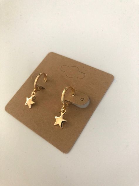 Small gold huggie hoops with dangling star charm. Lever back closure. 18K plated gold helps reduce sensitivity and make them hypoallergenic. Very lightweight style of earring that does not pull on ears at all. Simple style goes with every outfit! Cute Hoops Earrings, Gold Huggie Earrings With Charm, Gold Dainty Earrings, Dangly Gold Earrings, Gold Jewellery Earrings, Gold Piercings, Small Gold Earrings, Earrings Huggies, Gold Star Earrings