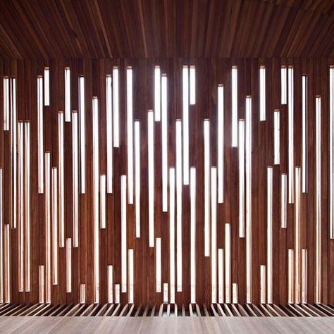 This Patterned Wood Wall is an amazing feature! The combination of the dark red wood panels with the bright white lights looks great! The use of having vertical lines help increase the appearance of height in the room, which is an added bonus! I love how the paneling blends straight into the ceiling and the floor!: Vinyl Fence Colors, Reka Bentuk Dalaman, Timber Screens, Wood Ceiling, Scandinavian Style Interior, Ceiling Ideas, Reclaimed Wood Wall, Partition Design, Light And Space