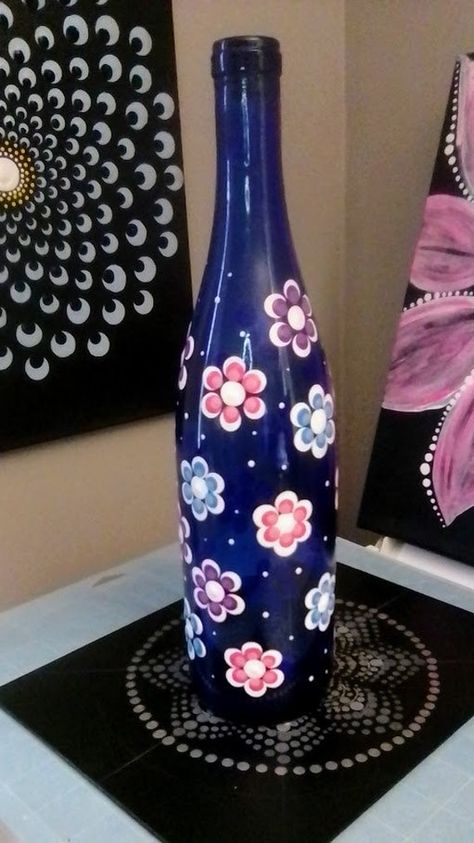 This unique wine bottle has been intricately hand painted with a beautiful dot mandala design. The stunning blue color and delicate flower theme make it a perfect decorative piece for any room in your home. This decorative bottle is a one-of-a-kind piece, perfect for anyone who appreciate art and unique home décor.  The style of this bottle is both modern and classic, making it perfect for any type of home. With hand-painted dot details and decorative features, this bottle is sure to be a conver Glass Bottle Art Diy Craft Projects, Glass Bottles Painting, Glass Bottle Painting, Bottle Art Projects, Blue Wine Bottles, Pink Mason Jars, Crafts With Glass Jars, Wine Bottle Wind Chimes, Painted Glass Bottles