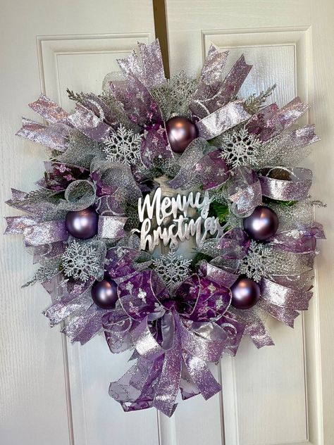 Stunning silver mesh covers this wreath along with three beautiful purple ribbons with glitter accents it also includes 5 purple ornaments and twinkle silver snowflakes. To top it off a silver merry Christmas sign in the middle Purple And Silver Christmas Wreath, Purple Mesh Wreaths For Front Door, Purple Wreath Ideas, Purple Wreaths For Front Door, Purple And Silver Christmas, Purple Christmas Tree Decorations, Purple Christmas Wreath, Plum Christmas, Silver Christmas Wreath