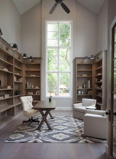 Amazing home office features a tall vaulted ceiling adorned with a ceiling fan over brown stained tall bookcases illuminated by black and gold swing-arm sconces. High Ceiling Office, Copper Kitchen Faucets, Office Built Ins, Meteor Garden 2018, Tall Ceilings, Transitional House, Small Home Office, High Walls, New Home Builders