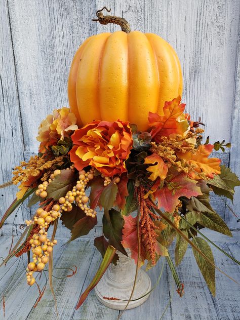 Enhance your home this Fall with this stunning Pumpkin Candlestick Table Arrangement. Perfect for adding a one of a kind seasonal decor piece on a table or mantle. Beautiful fall florals and foliage surround a bright orange pumpkin. The pumpkin is removable if you would prefer a candle to sit on top instead. Fall Lantern Centerpieces, Fall Candlesticks, Fall Topiary, Candle Table Decor, Pumpkin Candlesticks, Fall Lantern Decor, Candlestick Arrangements, Fall Topiaries, Candlestick Decor