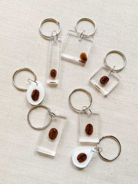 Real coffee beans cast in resin and made into keychains so that you can always have a bit of that extra coffee boost with you wherever you go! These are fun little gifts for your go to coffee buddy. And if you're a coffee shop send me an email to discuss wholesale pricing! callie@localpinescollaborative.com Approximate measurements of each style of keychain: *note that measurements are in CENTIMETERS!* 1 - 2.5 1.75 2 - 5 x 1.5 3 - 2.5 x 2.5 4 - 3 x 2 5 - 2.5 1.75 6 - 4 x 2 7 - 3 x 3 Choose the s Coffee Keychain, Real Coffee, Coffee Store, Custom Recipe, Unique Keychains, Diy Resin Crafts, Diy Resin, Great Coffee, Coffee Bean