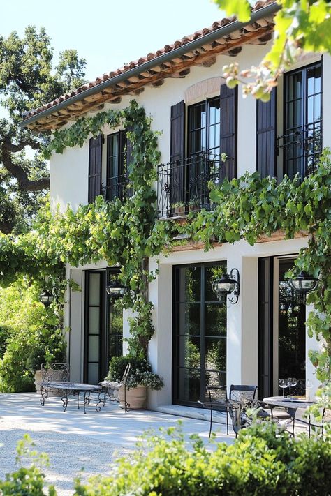 Modern French mediterranean house facade with shutters and climbing grape vines. Check out all of these charming French Mediterranean houses that are as modern as they are tres chic and make the ultimate dream retreats. Mediterranean Board And Batten, Mediterranean Revival Homes, Spanish House Colors, Patina Homes Exterior, Mideterranean House Aesthetic, French Mediterranean Home Exterior, Parisian Exterior Home, Provence France House, French Style Homes Exterior