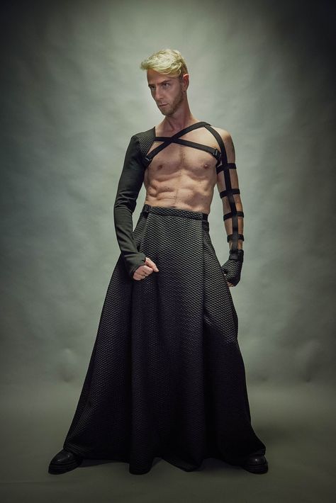 "Black men's maxi skirt with hidden pockets. It is made of a polyester jersey. The skirt has some stretch so it's comfortable for daily wear. The garment is sewn with Eloflex thread which minimizes the risk of seam breakdown on stretch fabrics. The skirt's belt fastens with a Fidlock magnetic buckle. Both, the inner belt and belt with the buckle are adjustable. The garment is easy to care for - cold machine wash, no tumble dry.  Key Features: - Adjustable waist. - Hidden pocket. - Made with spec Males In Dresses, Gender Bending Fashion Men, Flamboyant Poses Male, Fae Fashion Male, Weird Mens Fashion, Men’s Haute Couture, Men In Dresses Art, Extravagant Mens Fashion, Mens Cyberpunk Fashion